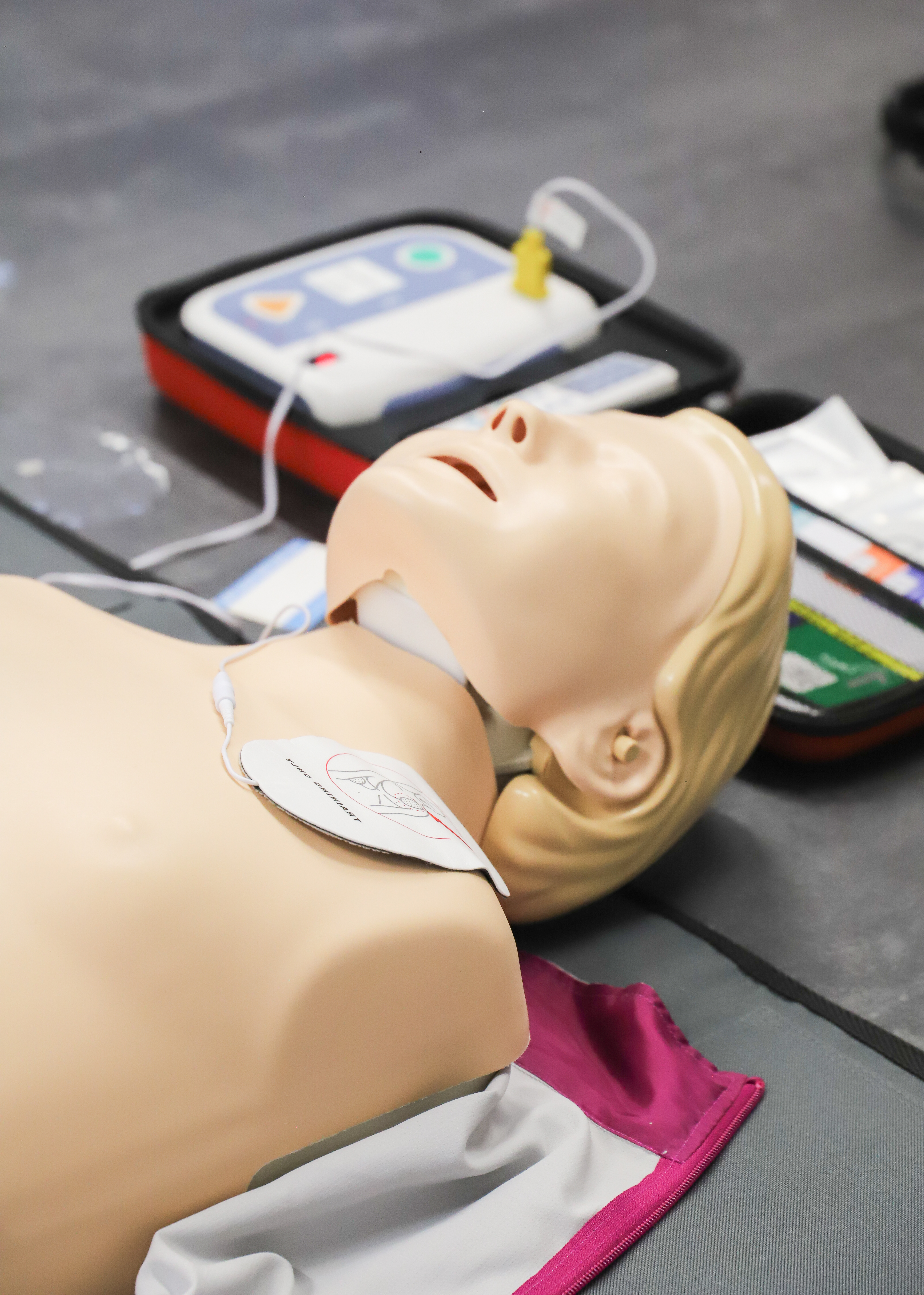 CPR training manikin fitted with defibrillator pads, used during first aid training